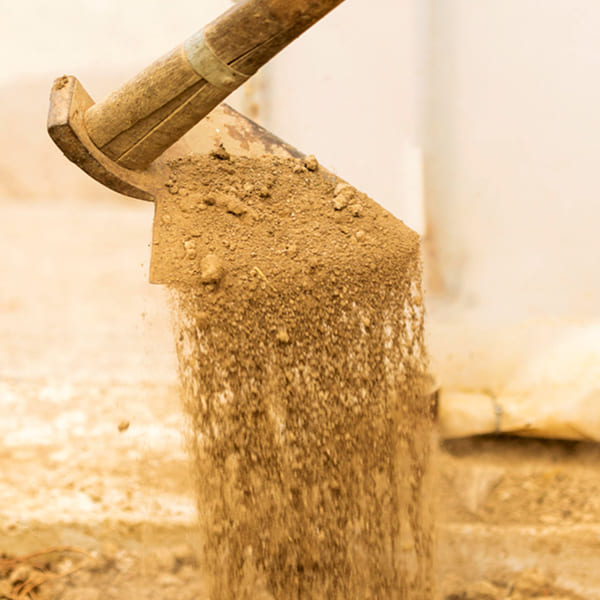 Pelle déversant du remblai contaminé lors de travaux d'extraction de pyrite sous une fondation